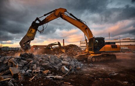 Modern crusher on excavator rigging dismantles concrete beam