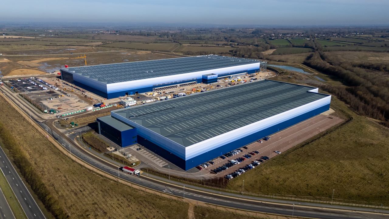 Large distribution center with loading docks and trucks parked outside, aerial view